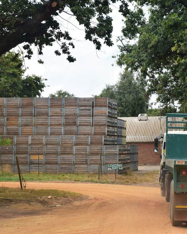 A farm truck loaded near stacked crates on a dirt road in South Africa
